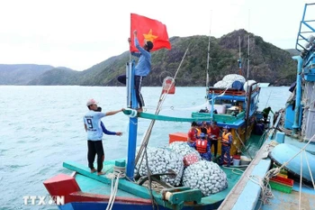 Fishermen prepare their vessels before setting sail, ensuring compliance with fishing regulations. (Photo: VNA)