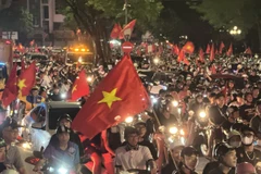 People take to Hanoi streets waving the national flag in celebration of the victory. (Photo: VNA)