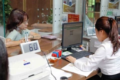 A customer conducts a transaction at a Vietcombank office in Hanoi. (Photo: VNA)