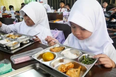 Students at an elementary school in Jakarta enjoy a free meal provided by the government for the first time. (Photo: asia.nikkei.com)