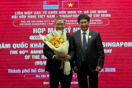 Chairman of the Vietnam–Singapore Friendship Association of Ho Chi Minh City Lam Dung Tien presents flowers to Singapore Consul General in HCM City Pang Te Cheng at the gathering. (Photo: sggp.org.vn)