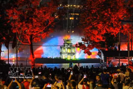 Large crowds gather around Hoan Kiem Lake to watch a 3D mapping light show projected onto Turtle Tower, accompanied by a water-screen display. (Photo: VNA)
