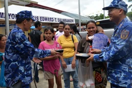 An officer of the Vietnam Coast Guard delegation presents meal portions to residents affected by the earthquake in Bogo province, the Philippines. (Photo: nhandan.vn)