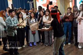 Young participants from India, Indonesia and Russia learn about the traditional pot-breaking game. (Photo: VNA)