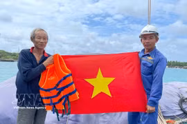 The naval force presents the national flag to a fisherman. (Photo: VNA)
