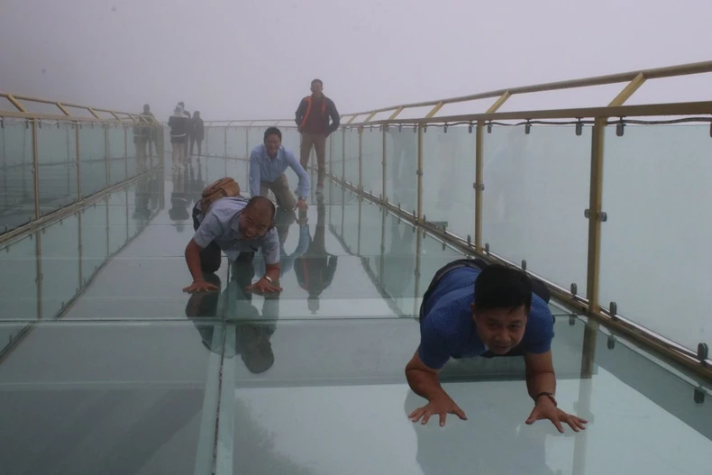 Tourists enjoy the experience of trying out various photo poses on Rong May glass bridge. (Photo: VNA) 