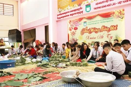 Teachers and students at the Nguyen Du Lao-Vietnamese bilingual language school in Vientiane make "chung" cakes. (Photo: VNA)