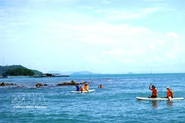Tourists enjoy stand-up paddleboarding (SUP) and foraging for seafood along the waters of the Hai Tac Archipelago. (Photo: VNA)