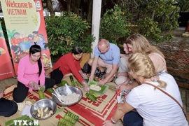 Foreign visitors experience making banh tet (cylindrical sticky rice cakes) (Photo: VNA) 