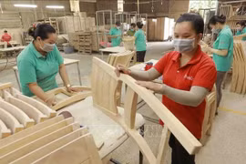 Workers make wooden furniture for export to the US, UK and EU markets at the factory of the Thiet Dan Two-Member Company Limited. (Photo: VNA)