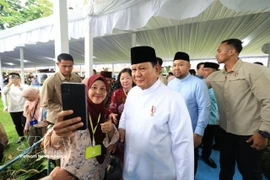 Indonesian President Prabowo Subianto poses for a photo with a visitor to the Presidential Palace of Indonesia in Jakarta. (Photo: VNA)