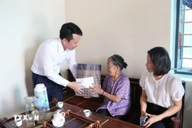 A woman who rendered meritorious services to the revolution receives gift (Photo: VNA)