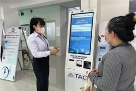 Long An General Hospital's staff guides a local resident on how to use the self-service medical check-in kiosk. (Photo: VNA)