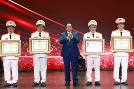 Prime Minister Pham Minh Chinh (middle) presents the Hero of the People’s Armed Forces title to outstanding individuals and collectives of the the People’s Public Security force. (Photo: VNA)