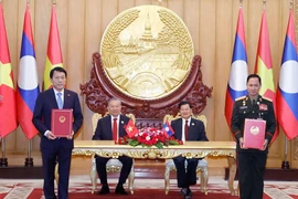 Vietnamese Party General Secretary To Lam (second, left), and Party General Secretary and President of Laos Thongloun Sisoulith witness the exchange of memorandum of understanding (MoU) on cooperation between the Vietnamese Ministry of Public Security and the Lao Ministry of National Defence on building a Vietnam - Laos friendship road. (Photo: VNA)