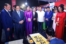 PM Pham Minh Chinh (front, second from left) and madam Ngo Phuong Ly (front, third from left), spouse of Party General Secretary To Lam, visits a Vietnamese booth at the event. (Photo: VNA)