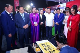PM Pham Minh Chinh (front, second from left) and madam Ngo Phuong Ly (front, third from left), spouse of Party General Secretary To Lam, visits a Vietnamese booth at the event. (Photo: VNA)