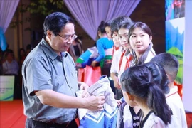Prime Minister Pham Minh Chinh presents coats to students in Bat Mot commune,Thanh Hoa province, on October 14. (Photo: VNA)