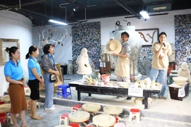 Visitors watch a traditional pottery-making demonstration at Bat Trang craft village. (Photo: hanoimoi.vn)