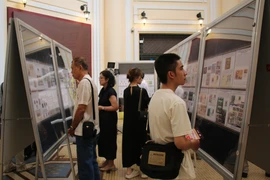Delegates look at stamp collections at the exhibition. (Photo: VNA)