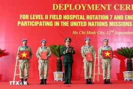 On behalf of the State President, Deputy Minister of National Defence Senior Lieutenant General Hoang Xuan Chien Hoang Xuan Chien presents the decision to Vietnamese units assigned to UN peacekeeping missions and hands over the national flag to them. (Photo: VNA)