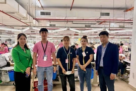 Le Ngoc Toan, First Secretary and Head of the Labour Management and Expert Committee in Malaysia (first, right) and First Secretary Thai Thi Huong (first, left) take a photo with Vietnamese workers at Ramatex Textiles factory in Johor. (Photo: VNA)