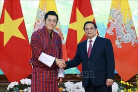 Prime Minister Pham Minh Chinh (R) welcomes King of Bhutan Jigme Khesar Namgyel Wangchuck in Hanoi on August 19. (Photo: VNA)