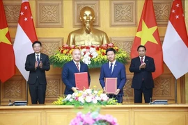 Prime Minister Pham Minh Chinh (R) and Singaporean Prime Minister Lawrence Wong (L) witness the exchange of the cooperation agreement between the Vietnam-Singapore Friendship Association and the Singapore International Foundation. (Photo: VNA)