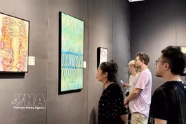 Visitors admire the paintings of Vietnamese-origin painter Van Guillemin (Photo: VNA)