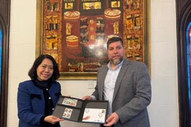 MP Victor Aldaya presents Ambassador Ngo Minh Nguyet with a set of stamps issued by Uruguay's National Post Office in December 2013, commemorating the 20th anniversary of Vietnam-Uruguay diplomatic relations. (Photo: VNA)