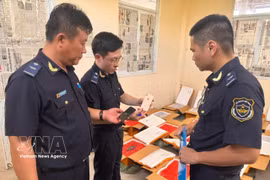 Customs officers conduct an inspection of a shipment of suspected used mobile phones in transit that lacks proper origin documentation (Photo: VNA)