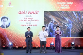 VNA General Director Vu Viet Trang (R) and Standing Vice Chairman of the Vietnam Journalists' Association Nguyen Duc Loi (L) present the first prize to Pham Tuan Anh at the event. (Photo: VNA) 