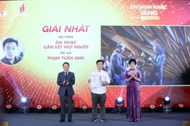 VNA General Director Vu Viet Trang (R) and Standing Vice Chairman of the Vietnam Journalists' Association Nguyen Duc Loi (L) present the first prize to Pham Tuan Anh at the event. (Photo: VNA) 