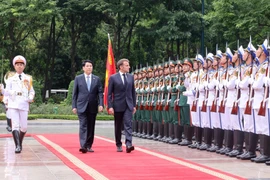 State President Luong Cuong (left) and French President Emmanuel Macron review the Guard of Honour of the Vietnam People’s Army. (Photo: VNA)