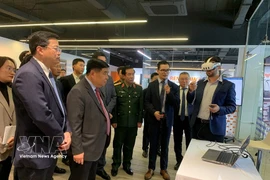 Deputy Prime Minister Nguyen Chi Dung and other delegates are briefed on R&D centre and COE on AI and Digital Twin at NEC. (Photo: VNA) 