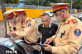 Traffic police officers present image evidence of a violation to a driver. (Photo: VNA)