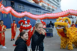 Tourists from Celebrity Solstice, the first cruise ship to arrive in Quang Ninh in 2026, enjoy taking photos with a Vietnamese lion and dragon dance troupe. (Photo: VNA)