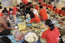 Guiding foreign friends to make square sticky rice cakes (Photo: qdnd.vn)