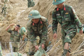Officers and soldiers of the Army Corps 34 clear roads to reach villages isolated by floods in Ngoc Linh commune, Quang Ngai province. (Photo: VNA)