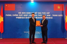 A representative of the Vietnamese delegation presents a souvenir to the Chinese delegation's representative at the conference (Photo: cand.com.vn)