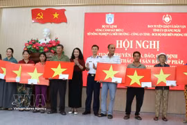 Representatives from the Coast Guard Region 2 Command and the Quang Ngai provincial Party Committee’s Board for Information, Education and Mass Mobilisation give gifts and national flags to fishermen. (Photo: VNA)
