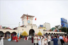 Tourists pose for photos in front of Ben Thanh Market, Ho Chi Minh City. (Photo: VNA)