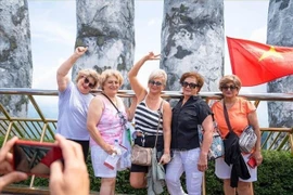 Foreign tourists enjoy checking in on the Golden Bridge in the Sun World Ba Na Hills complex in the central city of Da Nang. (Photo: VNA)