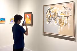 An art lover photographs a painting at the opening of the “Indonesia – Vietnam Art Dialogue” exhibition, which runs until June 5. (Photo courtesy of the gallery)