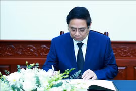 PM Pham Minh Chinh writes in the condolence book at the Lao Embassy in Vietnam. (Photo: VNA)