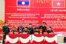 Representatives from Laos and Vietnam sign the agreement at the ceremony. (Photo published by VNA)