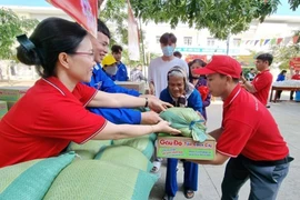 Staff members of the Ninh Thuan provincial Red Cross Society assist elderly people with difficult circumstances in transporting goods at a humanitarian market fair. (Photo: VNA)