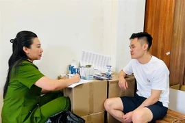 Pham Ngoc Tien is questioned by a police officer. (Photo: daibieunhandan.vn)