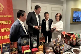 Trade Counsellor Tran Thu Quynh (first, right) introduces high-quality coffee products of Vietnam to Chairman of the Coffee Association of Canada Robert Carter (second from the left). (Photo: VNA)