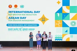 Deputy Minister of Agriculture and Environment Nguyen Hoang Hiep and Pauline Tamesis, UN Resident Coordinator in Vietnam present flowers to welcome WHO and IOM as new members of the disaster risk reduction partnership. (Photo: VNA) 